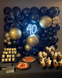 a 40th birthday party with black and gold balloons