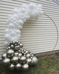 a balloon arch decorated with white and silver balloons