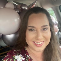 a woman sitting in the back seat of a car with balloons