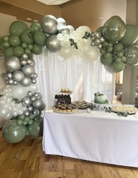 a balloon arch decorated with green and silver balloons